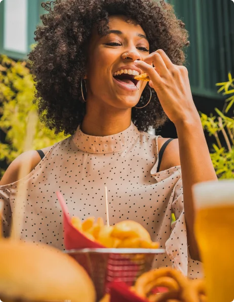 Mulher feliz comendo após usar o seu vale refeição